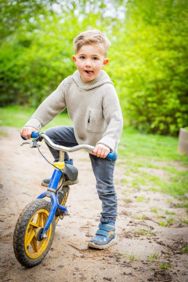 Ein Junge fährt auf einem Fahrrad, umgeben von grünem Gelände und Bäumen.