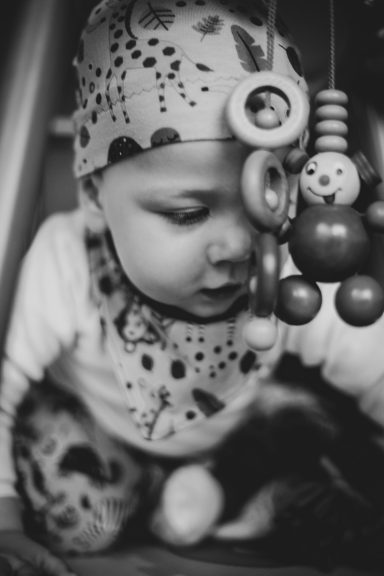 Ein kleines Kind spielt konzentriert mit bunten Spielzeugringen.