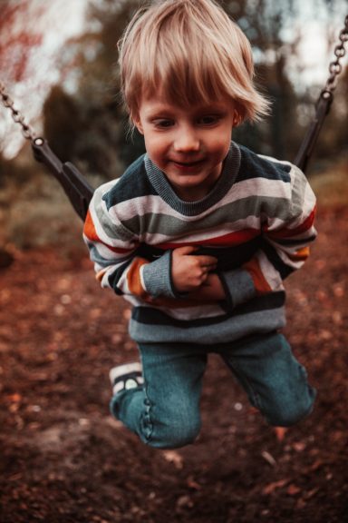Junge im gestreiften Pulli auf einer Schaukel
