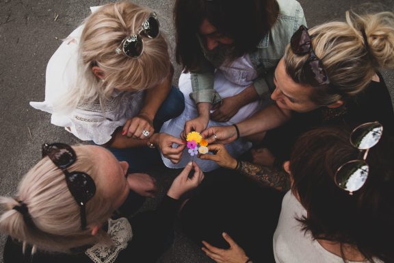Sechs Personen sitzen im Kreis und spielen mit einem bunten Spielzeug.