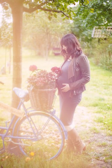 Frau mit einer blühenden Blumenkorb auf einem blauen Fahrrad in einem Park.