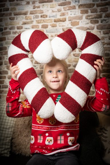 Ein Kind hält ein herzförmiges Kissen aus rot-weißen Zuckerstangen.