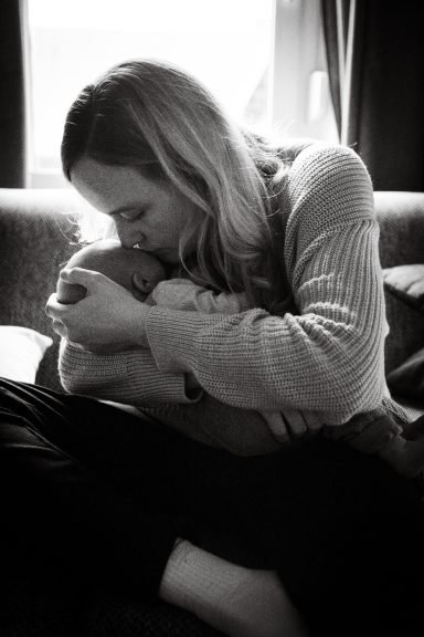 Eine Mutter umarmt ihr Baby liebevoll in einem gemütlichen Raum.