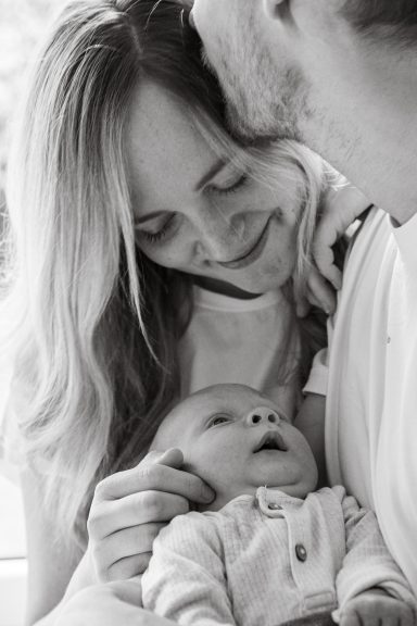 Eine Mutter umarmt liebevoll ihr Baby, während sie glücklich lächelt.