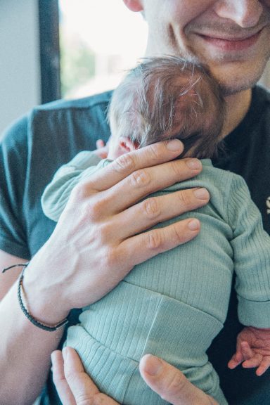 Vaterschaftsmoment: Ein Vater hält ein Baby im Arm, beide lächeln.