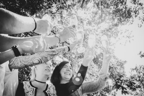 Drei Personen halten Lichter in einem sonnendurchfluteten Garten hoch.