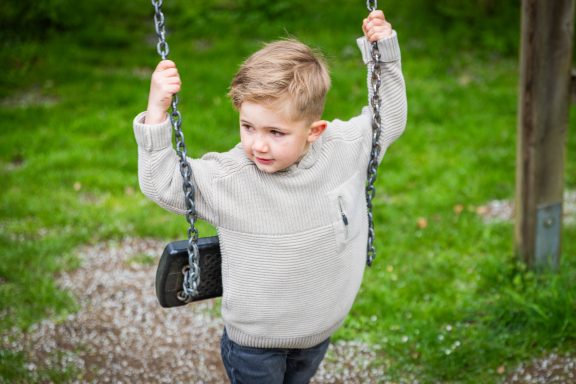 Ein Junge schwingt auf einer Schaukel in einem grünen Park.