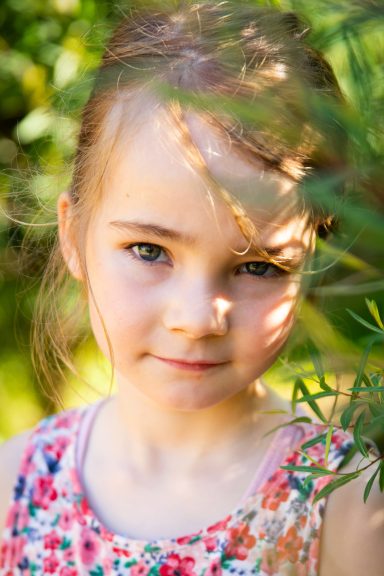 Ein Mädchen mit einem sanften Lächeln, umgeben von grünen Pflanzen.